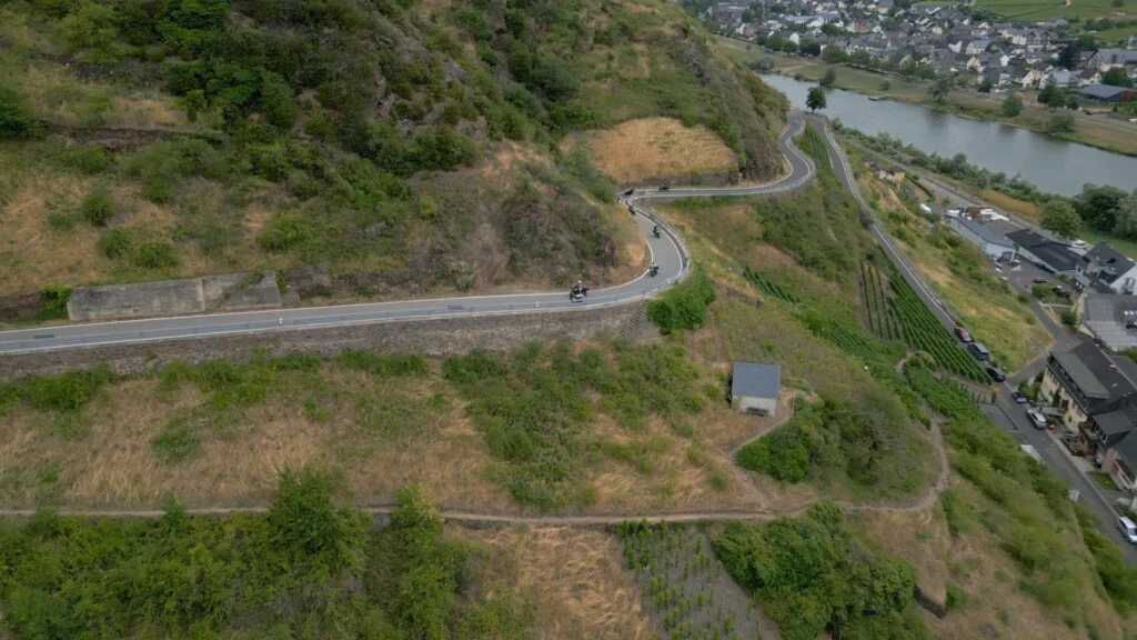 Motorrijders rijden door bochtige bergwegen langs wijnvelden en rivier