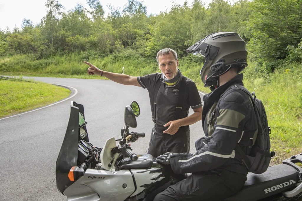 Motorrijinstructeur geeft persoonlijke uitleg aan motorrijder in de bergen